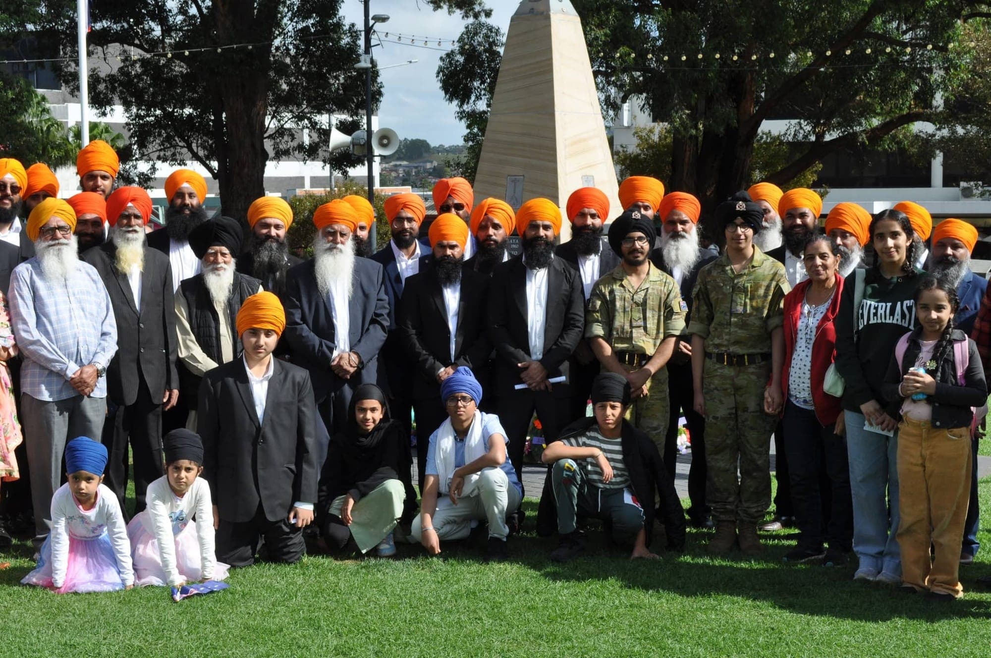 A large group of AKA members and community in orange turbans gathered at an ANZAC Day commemoration