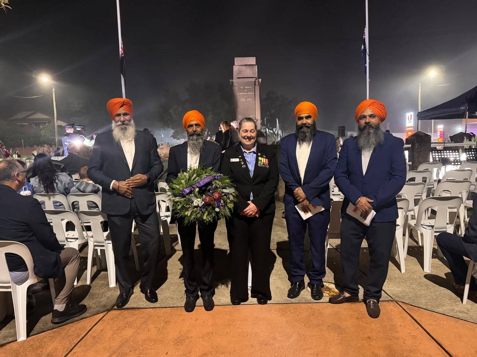 AKA members at an ANZAC Day dawn service holding a floral wreath