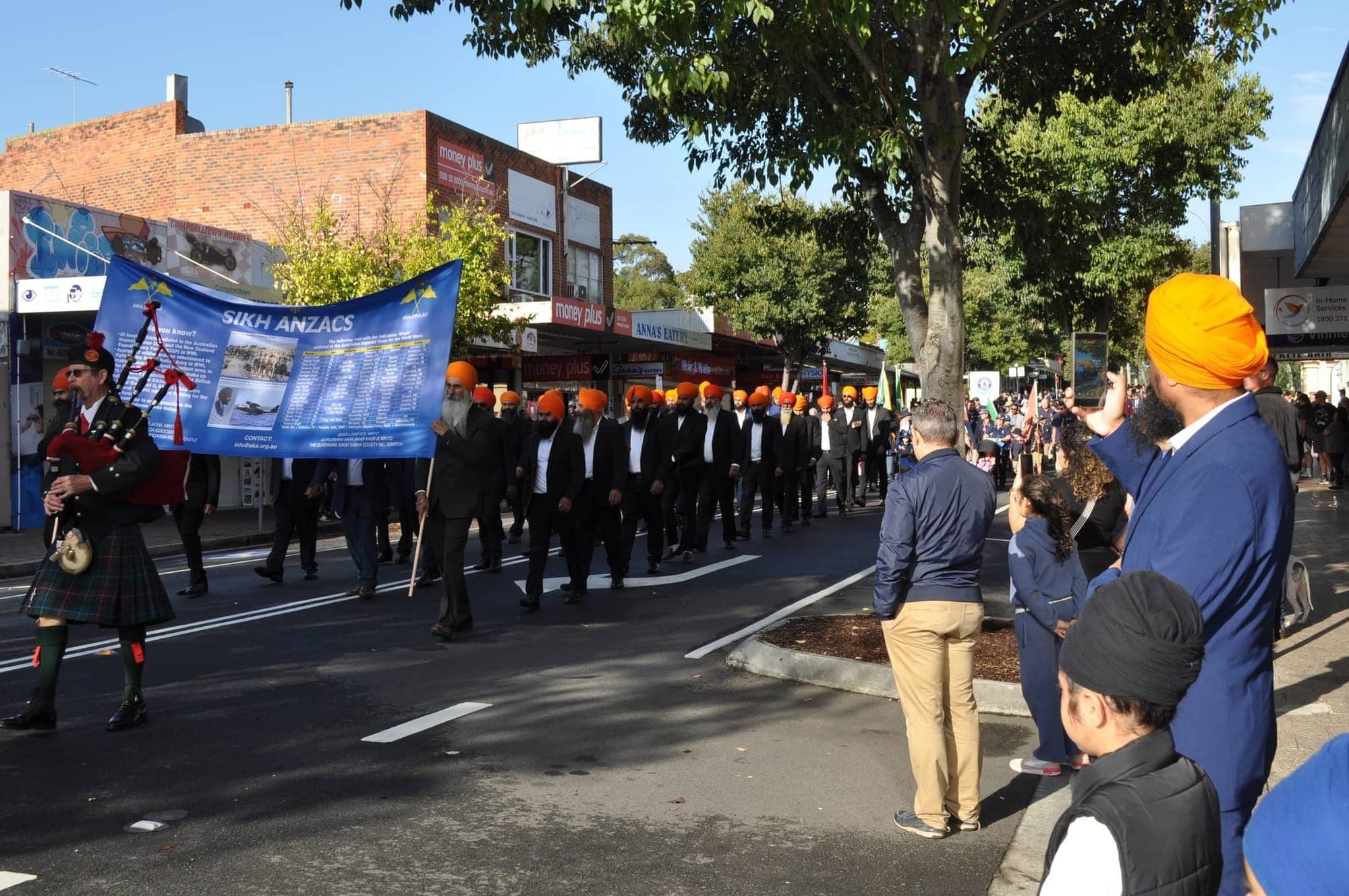 Members of the Australian Khalsa Association marching in dark suits beneath a Sikh ANZACs banner