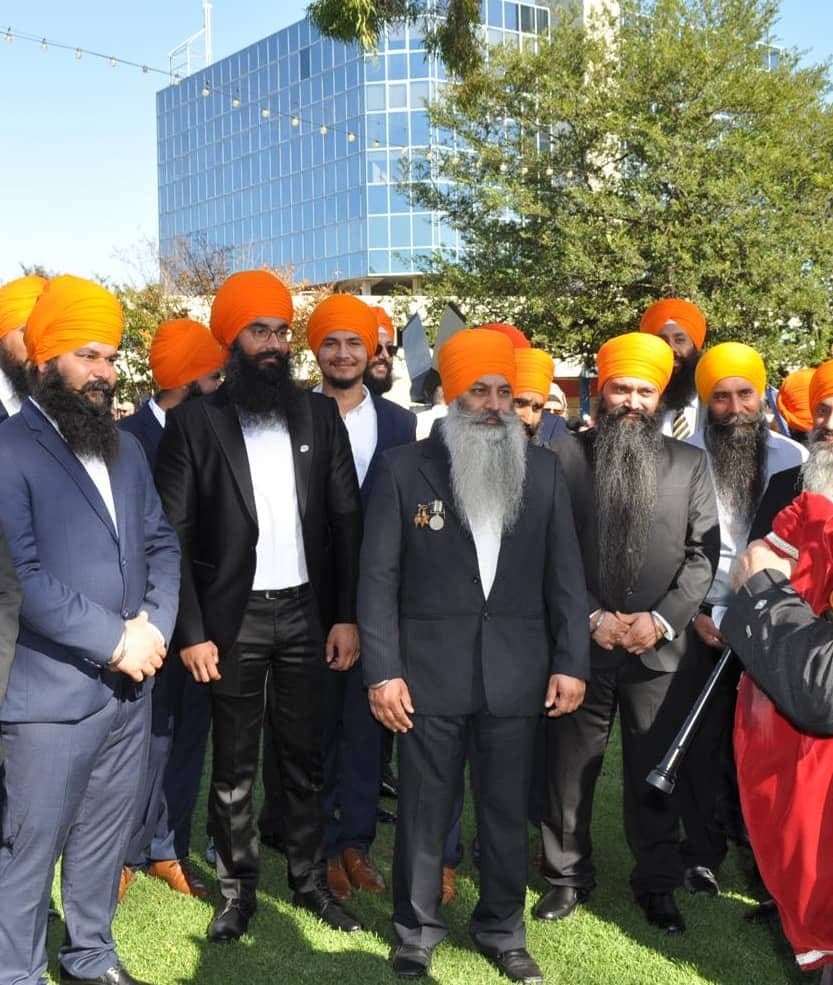 AKA members in suits and orange turbans standing on a lawn