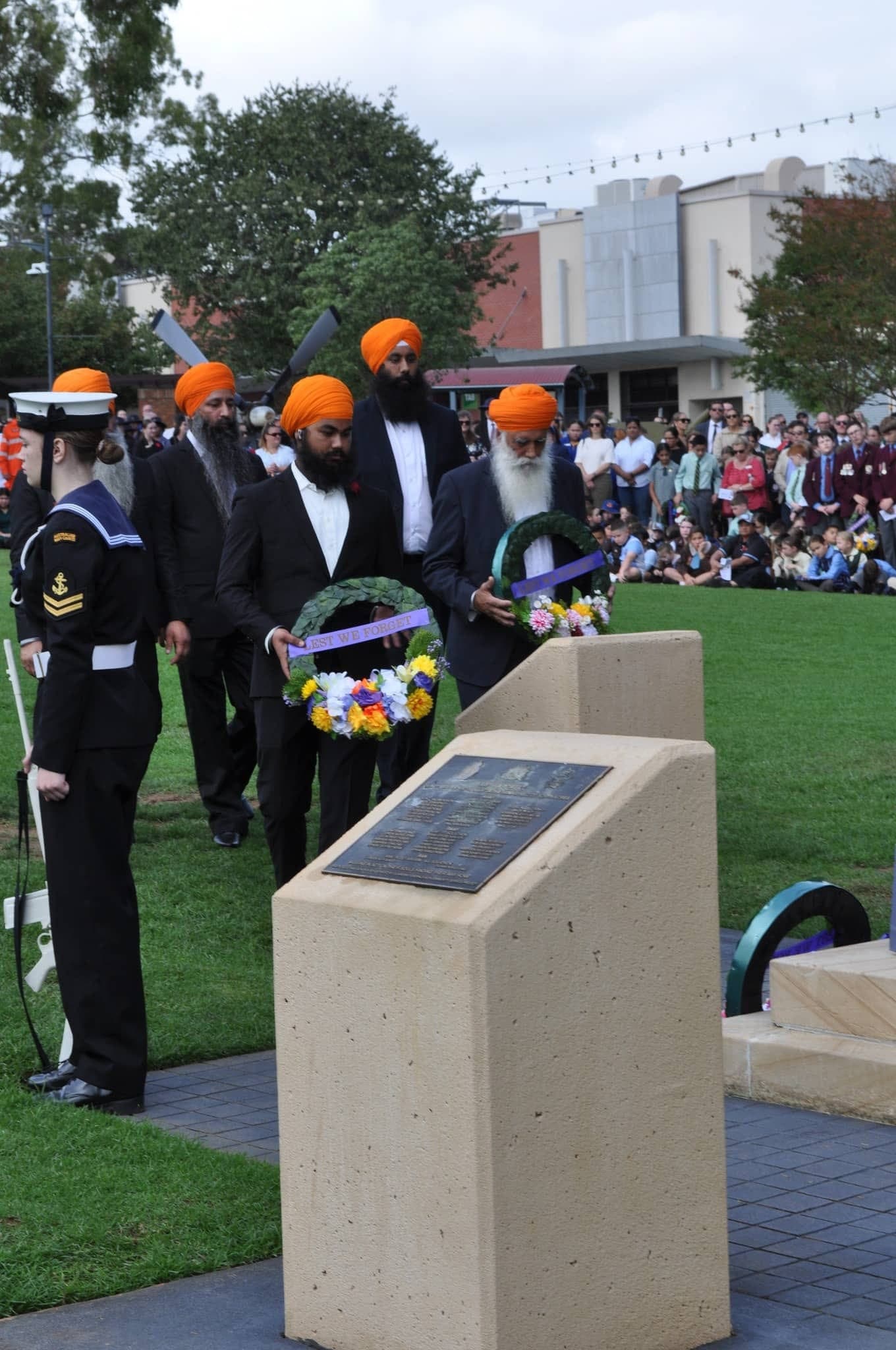 AKA representatives laying a wreath at a memorial alongside a uniformed service member
